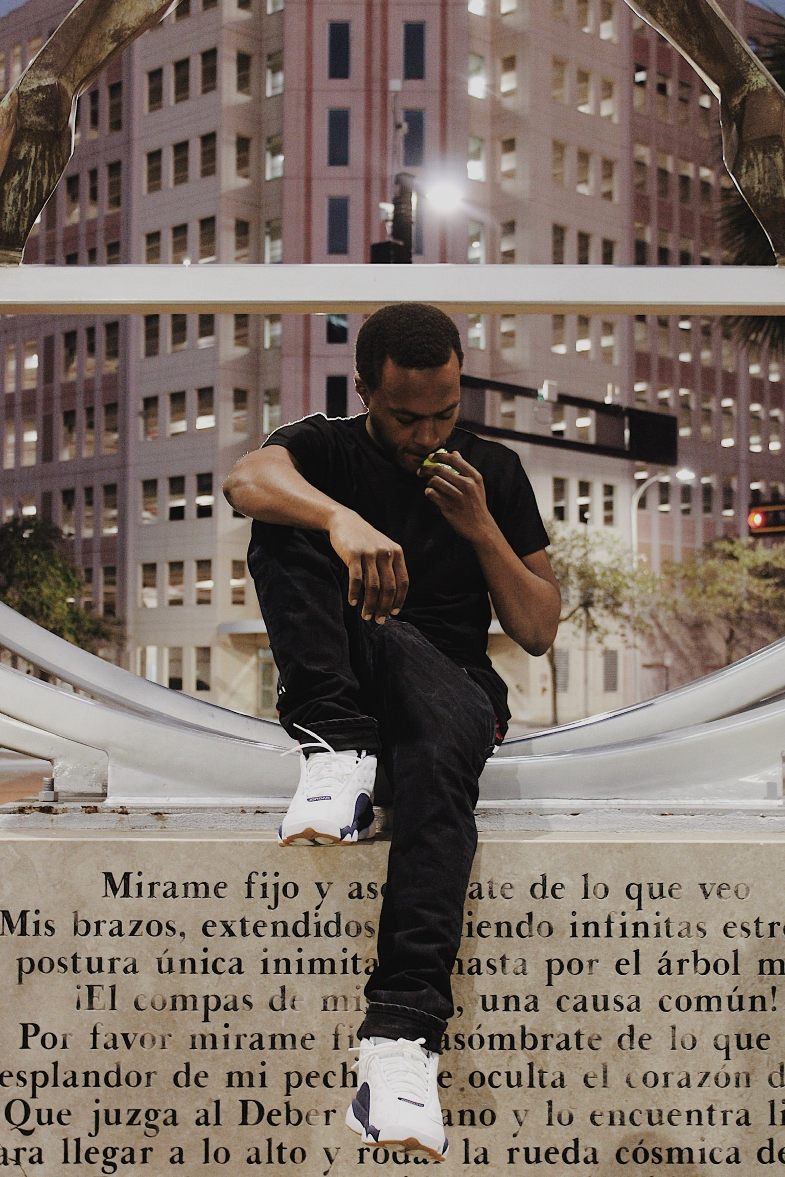 Man sitting on a ledge with a cityscape background