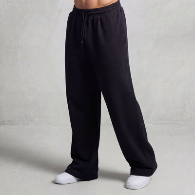 GMAN Essentials Loose Sweatpants in Black, oversized wide-leg fit, worn with white sneakers on a person.