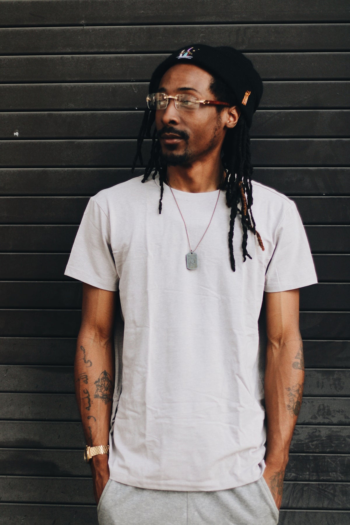 Man in a light gray GMAN tee against a dark wall